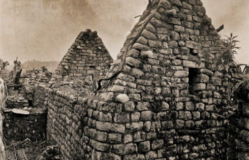 Foto: Hiram Bingham. Arquitectura inca. Una de las características más llamativas de la arquitectura de Machu Picchu es que la mayoría de las casas tiene una altura de un piso y medio y hastiales en los extremos. Los hastiales presentan unas piedras cilíndricas salientes que sugieren la antigua existencia de unas vigas de madera. En el caso de estas dos casas adyacentes sólo siguen en pie los hastiales de la cara sur; los del norte han sucumbido, bien a los terremotos, bien a la fuerza destructora de la vegetación.