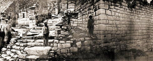 Foto: Hiram Bingham. El centro de la ciudad concentra los ejemplos de cantería más exquisitos. A la derecha se aprecia el hermoso muro exterior del grupo caracterizado por contar con los hastiales más inclinados y los dinteles monolíticos de mejor factura. En el centro se ve un trecho de la escalera más larga. En el extremo izquierdo se distingue una parte de la torre semicircular y la ventana de las serpientes.